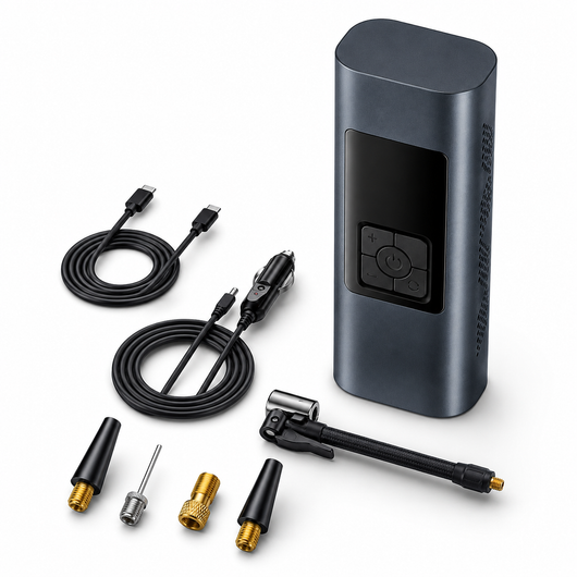 A portable electric air pump kit with a dark gray rectangular pump body, shown with multiple accessories on a clean white background. The kit includes two black USB-C to car adapter cables, four nozzle tips (two black, one silver, one gold), and a black quick-release hose clamp.